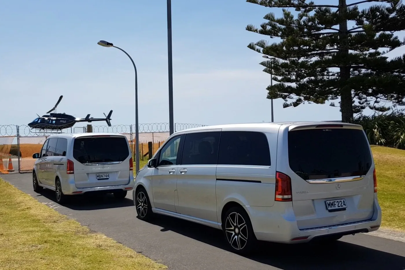 Titanium Mercedes vehicles beside a helicopter